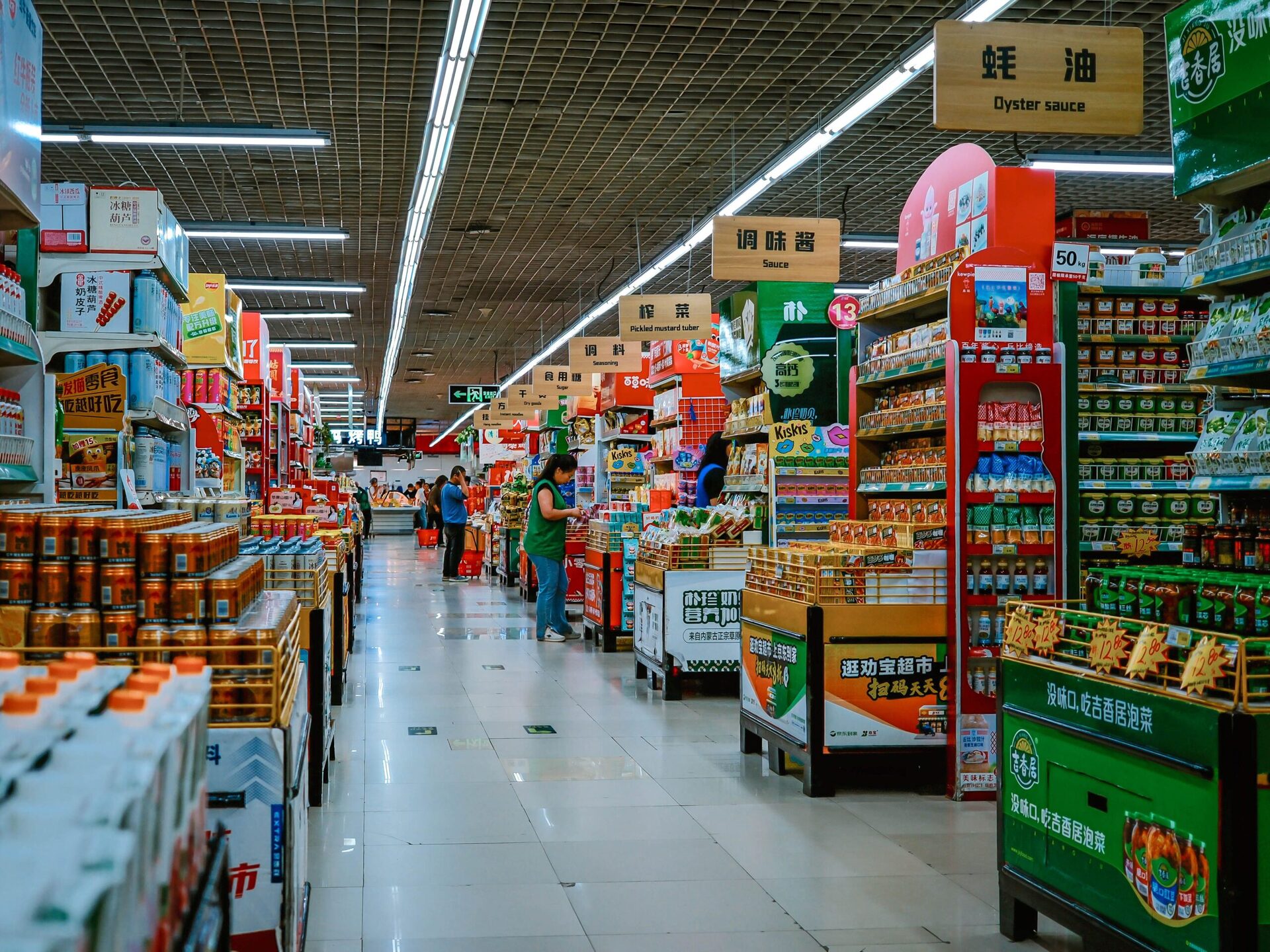 Silk Fabric Banarasi Pure (5.5m Saree Length) 1 A vibrant supermarket aisle filled with diverse products and shoppers under bright lighting.