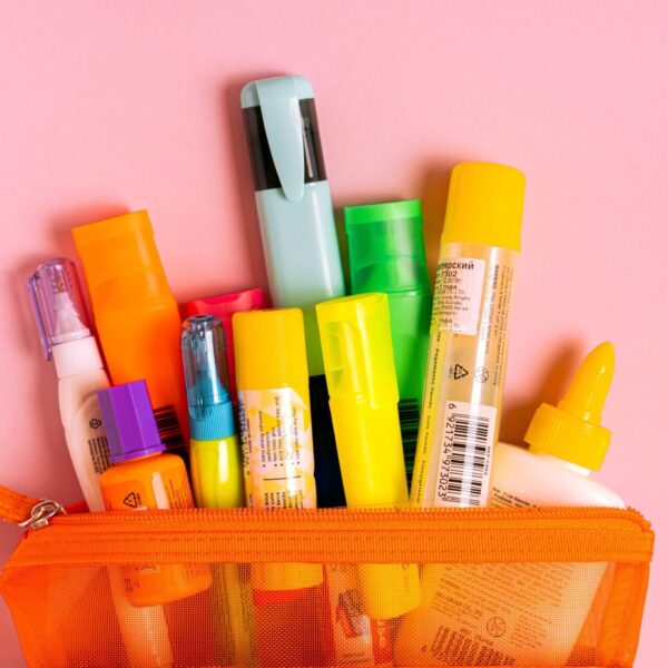 Bright office essentials in a mesh pouch on a pink background. Perfect for stationery enthusiasts.