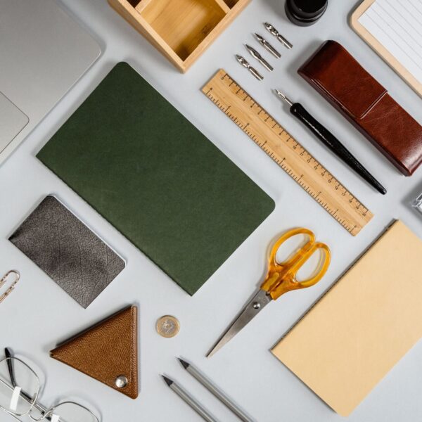 Organized flat lay of office supplies featuring a laptop, pens, scissors, and notebooks.